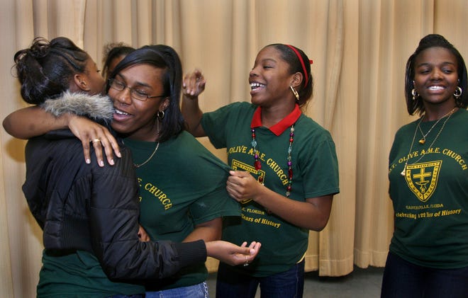 011708--Gainesville, Fla.-- Mt. Olive A.M.E. Church team captain Nicole Brown hugs Michaela Bean and celebrates with teammates Charmian Akins and Danielle Brown after the team won the 3rd Annual King Celebration Cultural Brain Bowl at the MLK center Thursday night. (Photo by: Brad McClenny/ Special to the Sun)