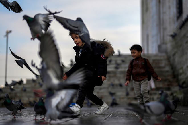 January 17, 2024: Children play with pigeons next to Yeni Cami (New Mosque) in Istanbul, Turkey.