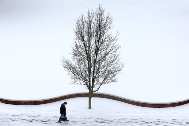 January 19, 2024 : A lone pedestrian walks along snow covered Exchange Street near the University of Akron in Akron, Ohio.