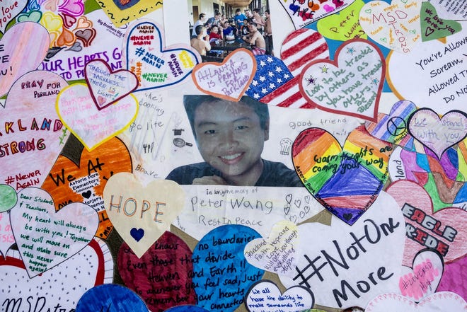 Posters, including this one of student Peter Wang, are hung on display during an interfaith ceremony honoring the memory of those who lost their lives at MSD High School last year, Thursday evening inside Pine Trails Park, in Parkland, Florida. [RICHARD GRAULICH/palmbeachpost.com]